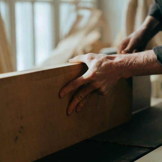 Close-up of a craftsman's hands working with wood in a workshop setting.